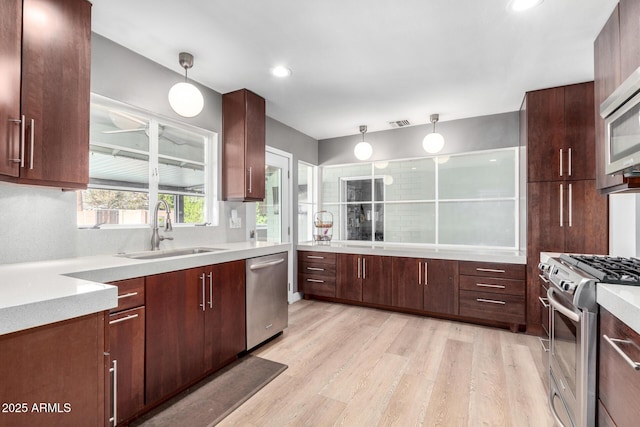 kitchen featuring sink, decorative light fixtures, stainless steel appliances, and light hardwood / wood-style floors