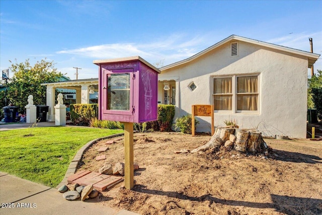 view of front of home featuring a front yard and stucco siding
