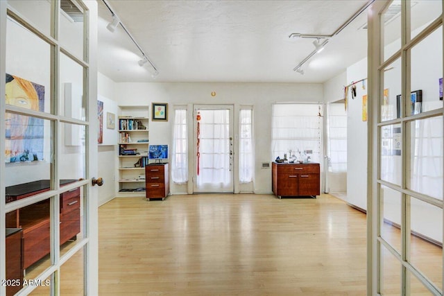 interior space featuring french doors, a textured ceiling, rail lighting, and wood finished floors