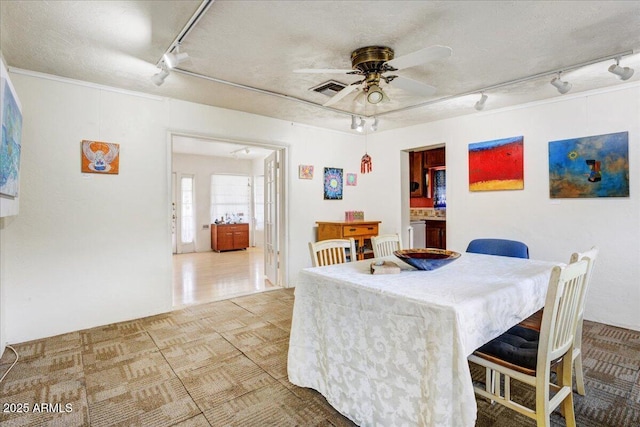 dining space featuring visible vents, track lighting, washer / dryer, a textured ceiling, and a ceiling fan
