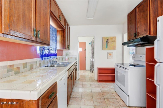 kitchen with under cabinet range hood, a sink, tile countertops, white appliances, and light tile patterned floors