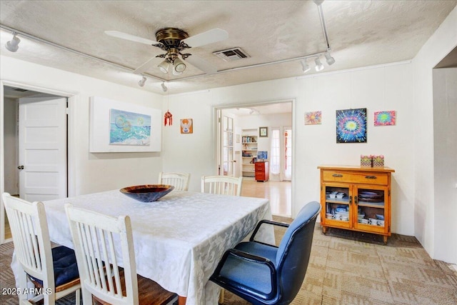 dining room featuring visible vents, a textured ceiling, track lighting, and ceiling fan