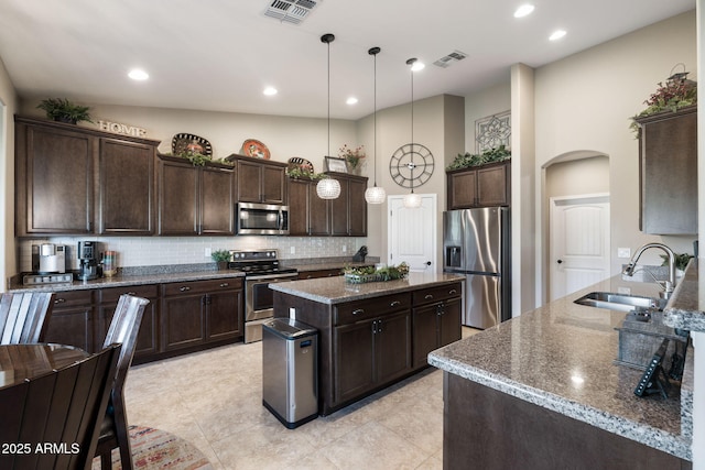 kitchen featuring arched walkways, visible vents, stainless steel appliances, and a sink