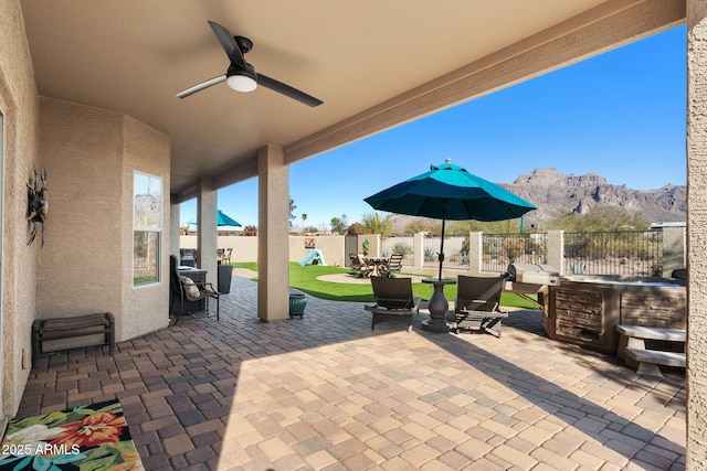 view of patio with a mountain view, a ceiling fan, and a fenced backyard