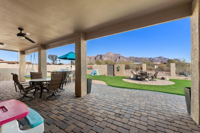 view of patio featuring ceiling fan, a mountain view, a fenced backyard, and outdoor dining space