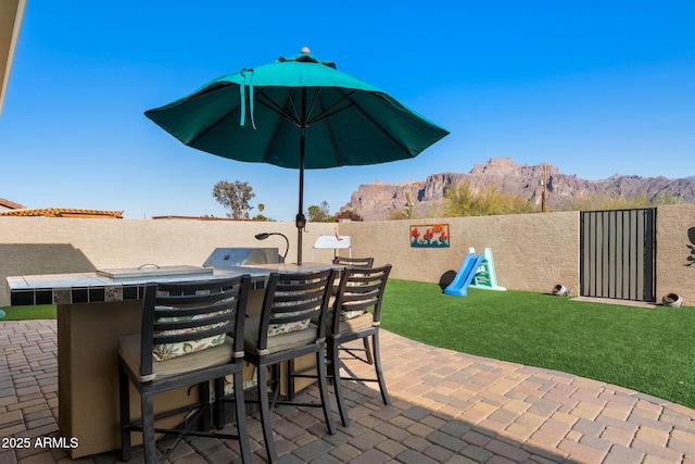 view of patio featuring outdoor dry bar, outdoor dining space, a mountain view, and a fenced backyard