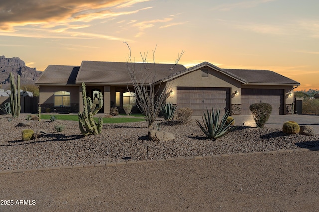 ranch-style home featuring stucco siding, a tiled roof, an attached garage, and driveway