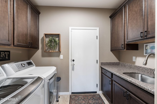 laundry room with a sink, baseboards, cabinet space, and separate washer and dryer