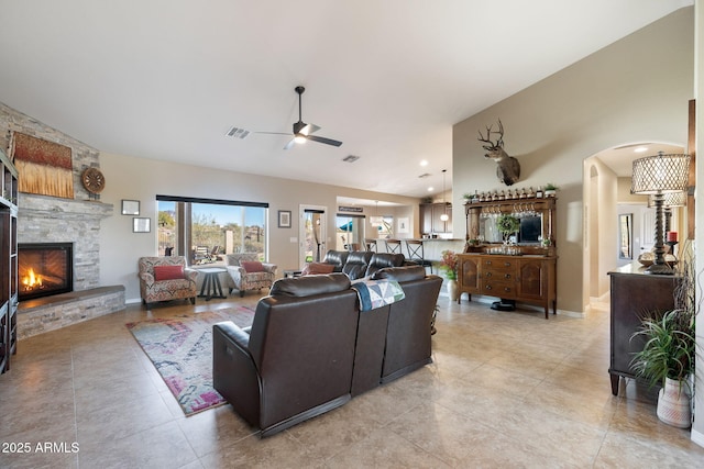 living area with visible vents, a ceiling fan, arched walkways, a fireplace, and lofted ceiling