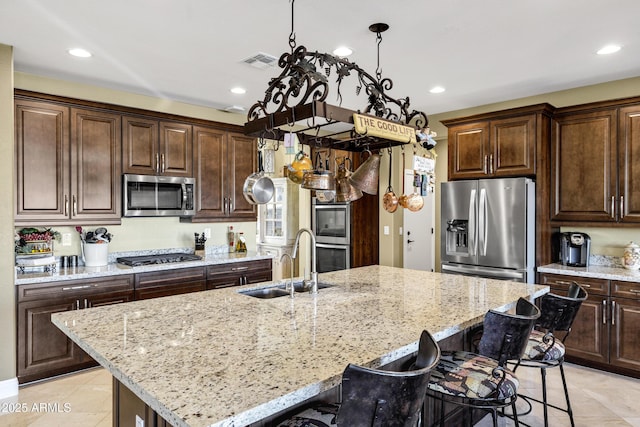 kitchen with a kitchen island with sink, sink, pendant lighting, and stainless steel appliances