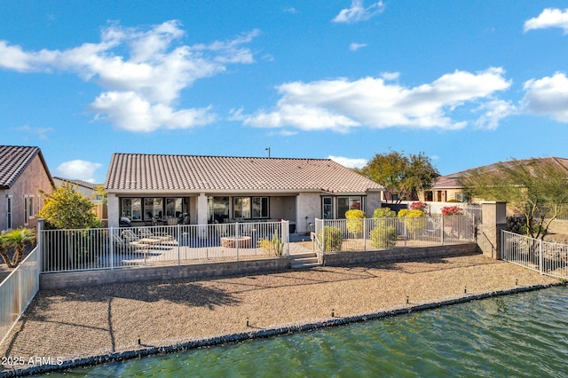 back of house with a water view and a patio