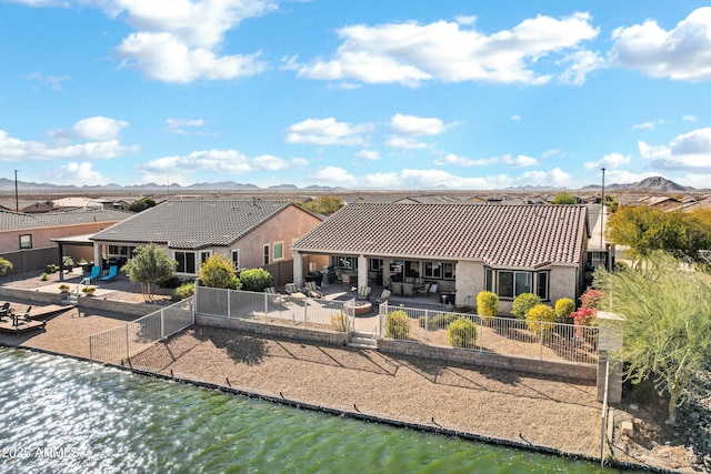 back of house featuring a water and mountain view and a patio area