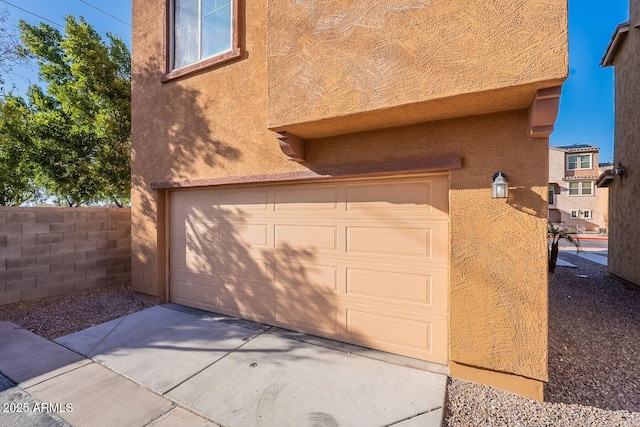 garage with concrete driveway and fence