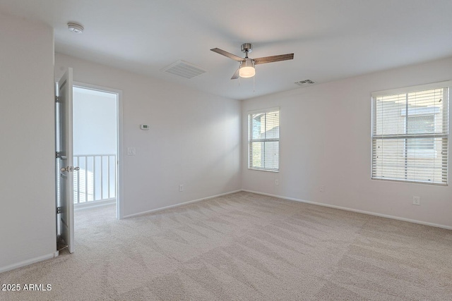 spare room with light carpet, visible vents, baseboards, and a ceiling fan