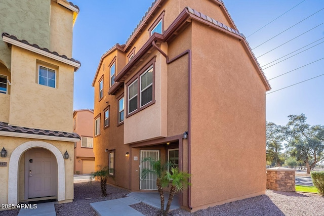 view of property with stucco siding and a tiled roof