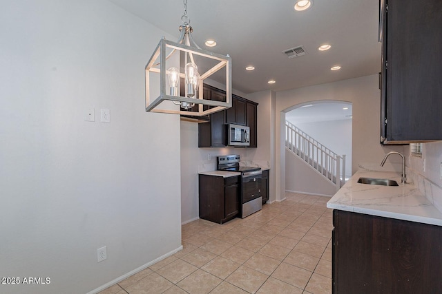 kitchen featuring visible vents, a sink, arched walkways, appliances with stainless steel finishes, and dark brown cabinets