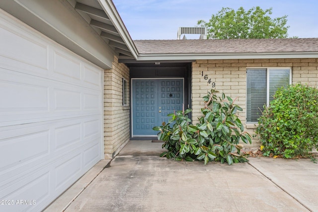1649 W Royal Palm Rd, Phoenix, AZ 85021 - view of exterior entry with a shingled roof, brick siding, driveway, and a garage