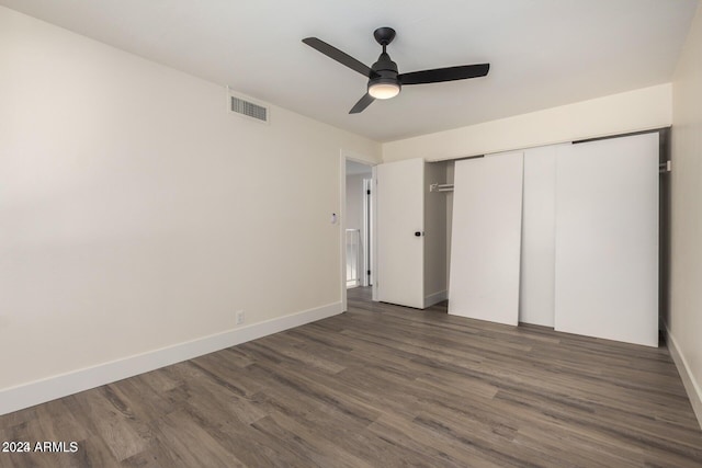 unfurnished bedroom featuring ceiling fan, a closet, and dark wood-type flooring