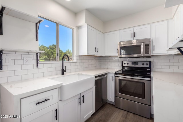 kitchen featuring sink, decorative backsplash, light stone countertops, white cabinetry, and stainless steel appliances