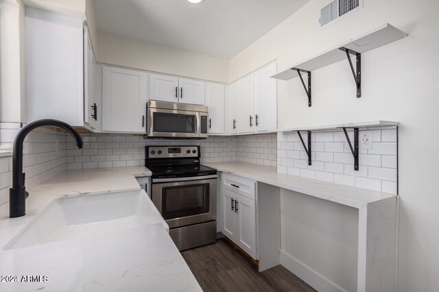 kitchen featuring dark hardwood / wood-style floors, light stone counters, white cabinetry, and appliances with stainless steel finishes