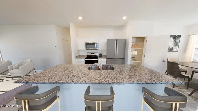 5781 E Iris Dr, Florence, AZ 85132 - kitchen featuring appliances with stainless steel finishes, a sink, white cabinetry, a breakfast bar area, and recessed lighting