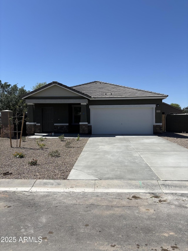 5781 E Iris Dr, Florence, AZ 85132 - view of front facade featuring driveway, a garage, a tile roof, stone siding, and stucco siding