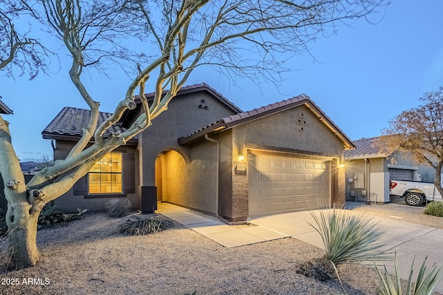 view of front of property featuring a garage, a tile roof, concrete driveway, and stucco siding