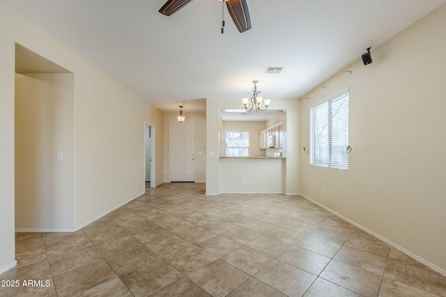 unfurnished living room with ceiling fan with notable chandelier, light tile patterned flooring, baseboards, and visible vents