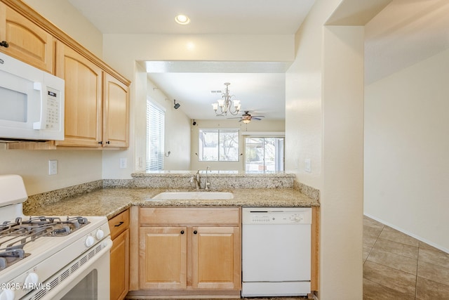 kitchen featuring light brown cabinetry, a sink, white appliances, an inviting chandelier, and light tile patterned floors