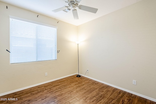 unfurnished room with a healthy amount of sunlight, ceiling fan, baseboards, and wood finished floors