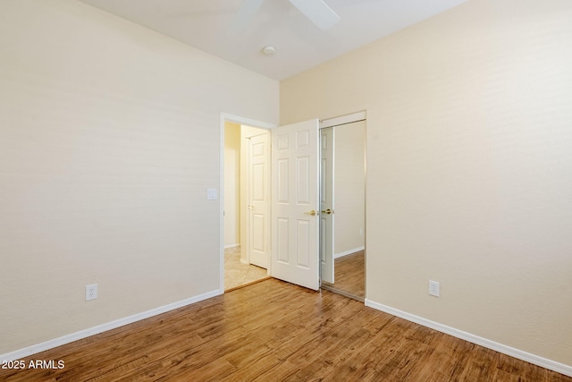 unfurnished bedroom with a closet, baseboards, wood finished floors, and a ceiling fan