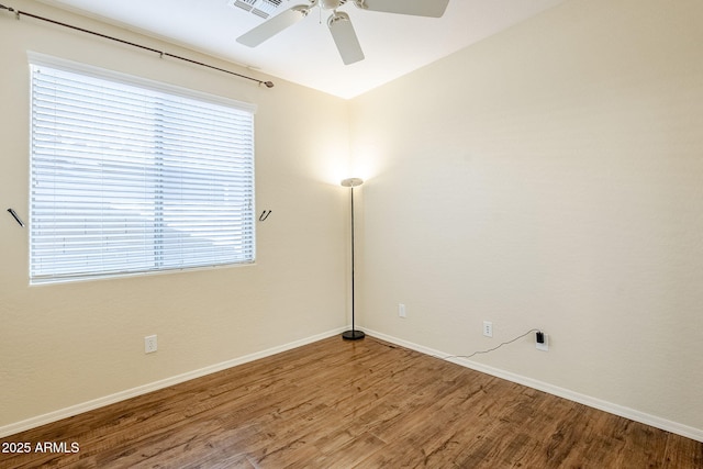 spare room featuring a ceiling fan, baseboards, and wood finished floors