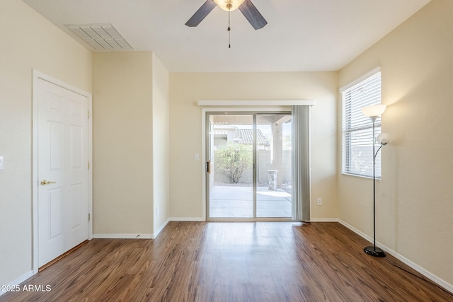 spare room with wood finished floors, visible vents, and baseboards