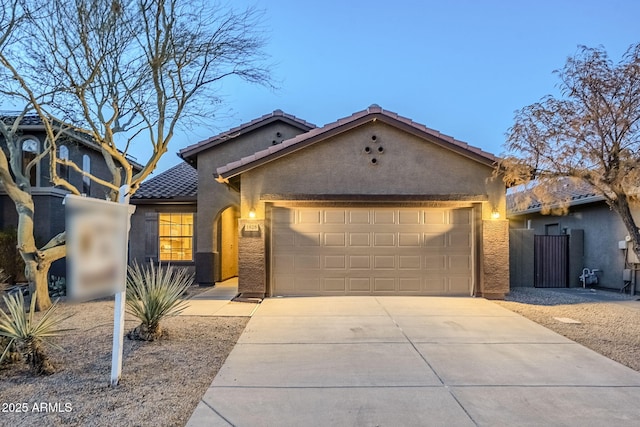 view of front facade with a tile roof, a garage, driveway, and stucco siding