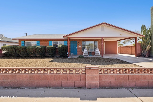 view of front of home featuring covered porch, an attached carport, driveway, and fence