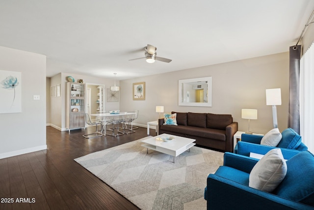 living area with a ceiling fan, baseboards, and dark wood-style flooring