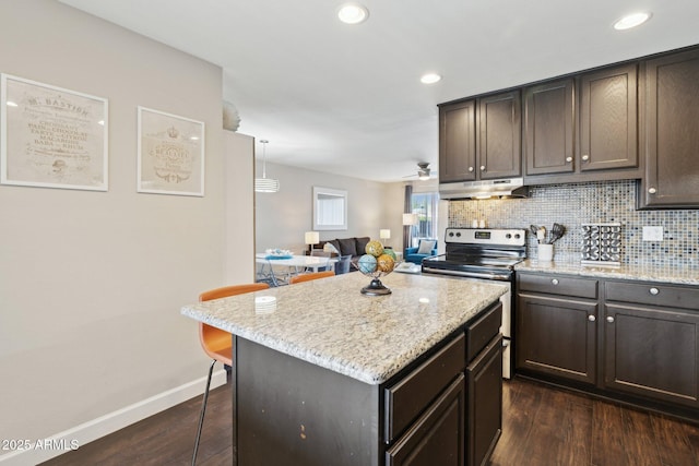 8107 E Mitchell Dr, Scottsdale, AZ 85251 - kitchen with backsplash, dark wood-type flooring, under cabinet range hood, a breakfast bar, and stainless steel electric range oven