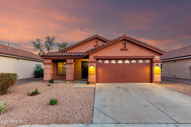 view of front facade featuring covered porch, stucco siding, concrete driveway, an attached garage, and a tile roof