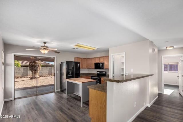 kitchen featuring baseboards, dark wood-style flooring, black appliances, and a peninsula