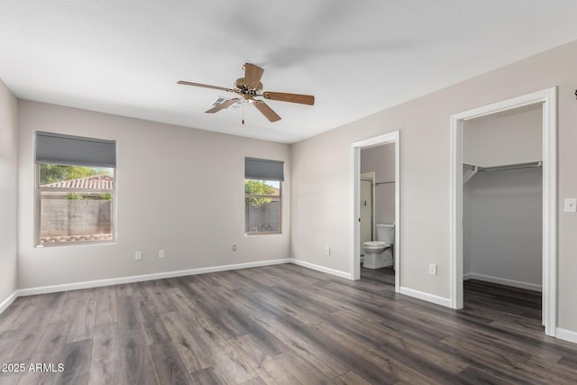 unfurnished bedroom featuring a spacious closet, multiple windows, and dark wood-style floors