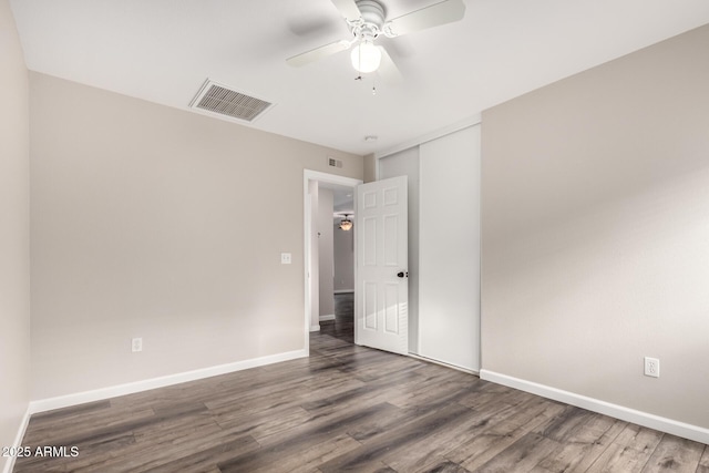 unfurnished bedroom with baseboards, a closet, wood finished floors, and visible vents
