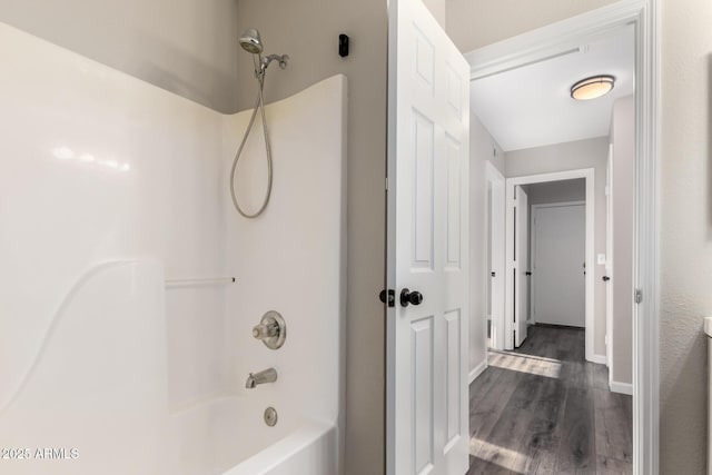 bathroom with baseboards, tub / shower combination, and wood finished floors