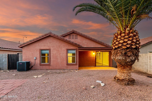 view of front of home featuring stucco siding, central AC unit, fence, and a tiled roof