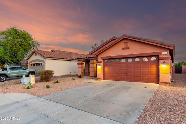 view of front of property featuring a garage, stucco siding, driveway, and a tiled roof