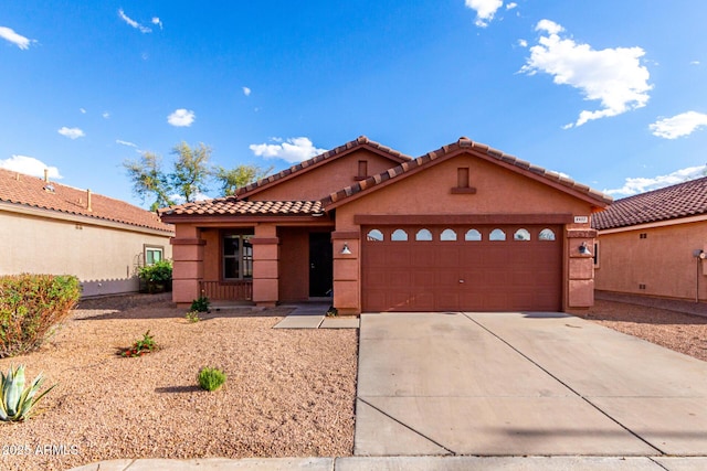 view of front of house featuring a tiled roof, stucco siding, driveway, and a garage
