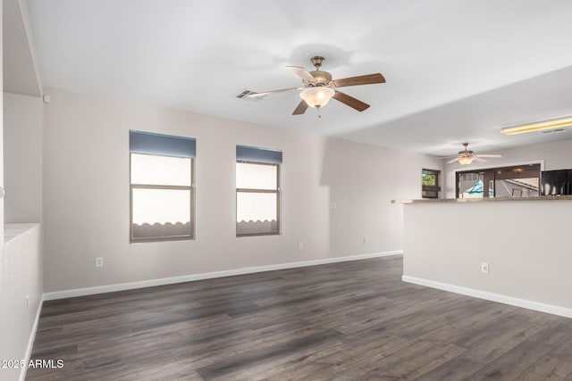 unfurnished room with ceiling fan, visible vents, baseboards, and dark wood-type flooring