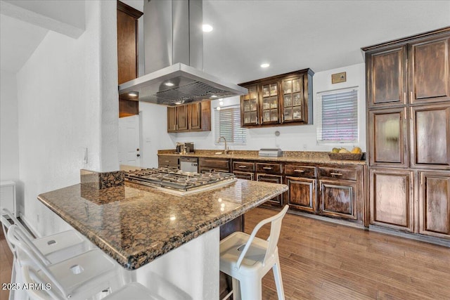 6747 N 12th St, Phoenix, AZ 85014 - kitchen featuring a breakfast bar area, stainless steel gas cooktop, island exhaust hood, dark stone counters, and light wood-style flooring