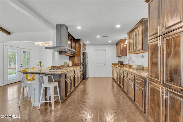 6747 N 12th St, Phoenix, AZ 85014 - kitchen featuring light wood-type flooring, a sink, stainless steel gas cooktop, and wall chimney exhaust hood