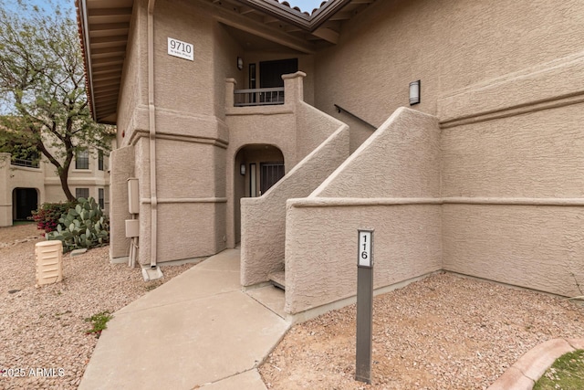 exterior space with a tiled roof, a balcony, and stucco siding