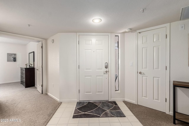 foyer with baseboards, a textured ceiling, and light colored carpet